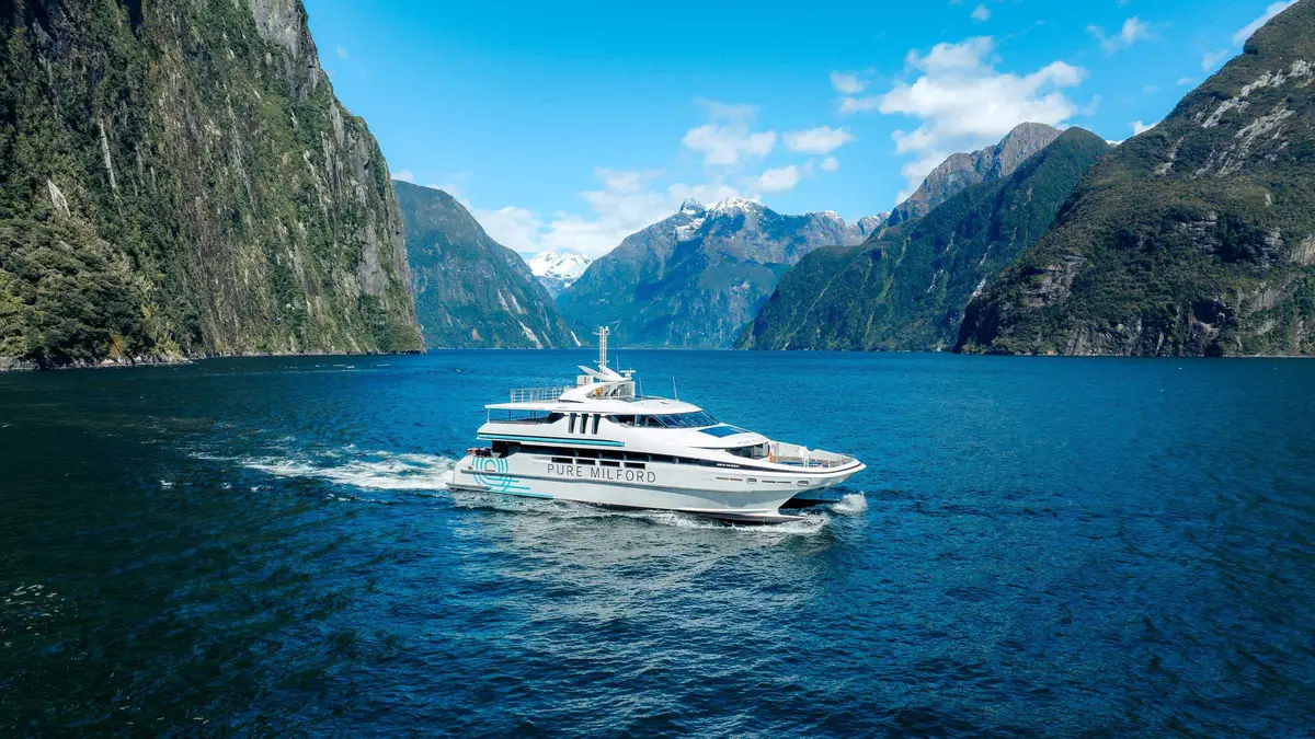 Glass-roof catamaran on a Milford Sound nature cruise below steep fiord walls in Fiordland, New Zealand