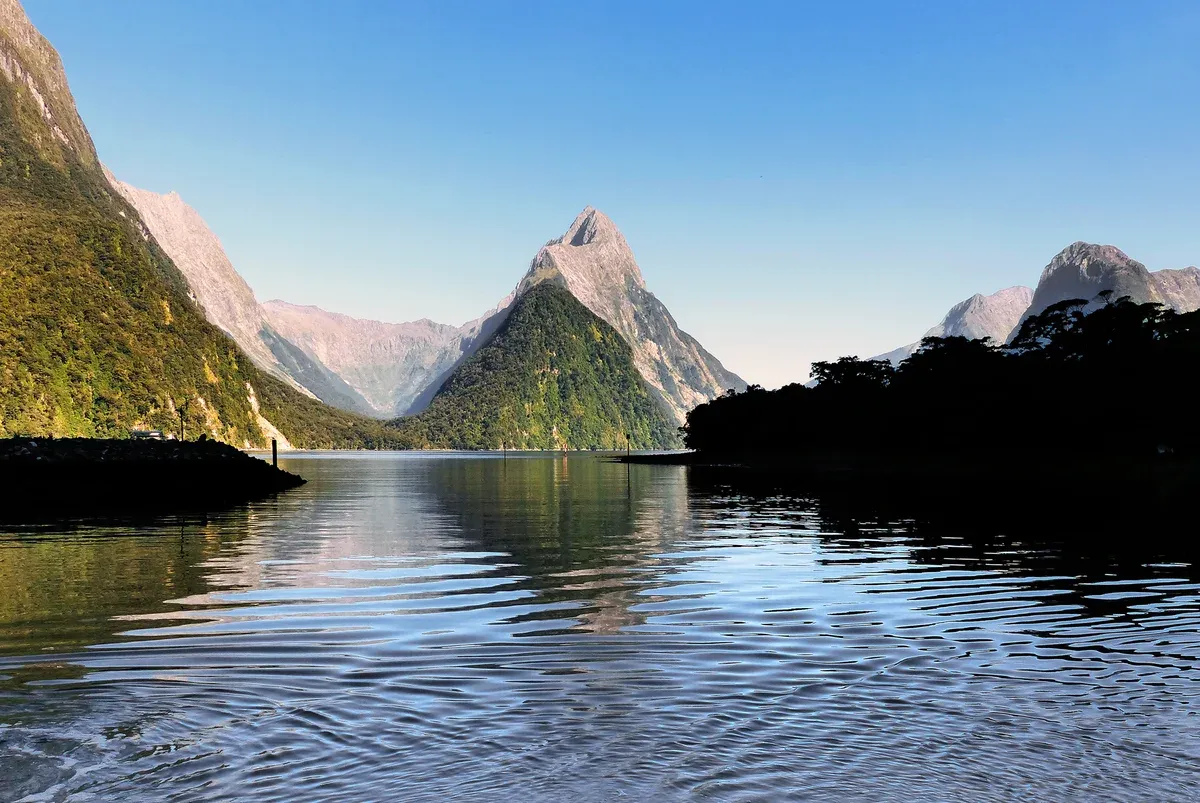 Mitre Peak rising from calm water on a clear morning, the first sight on a Milford Sound boat tour
