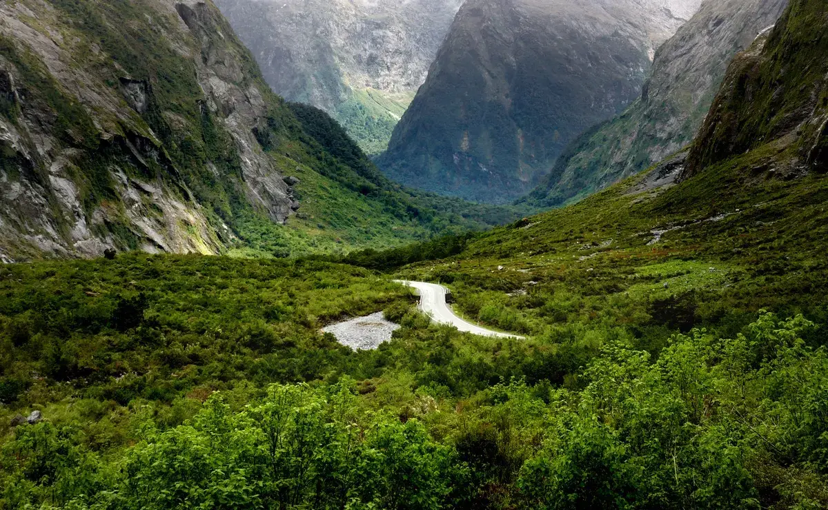 Cleddau Valley with a winding track below steep peaks, seen on the road to a Milford Sound cruise