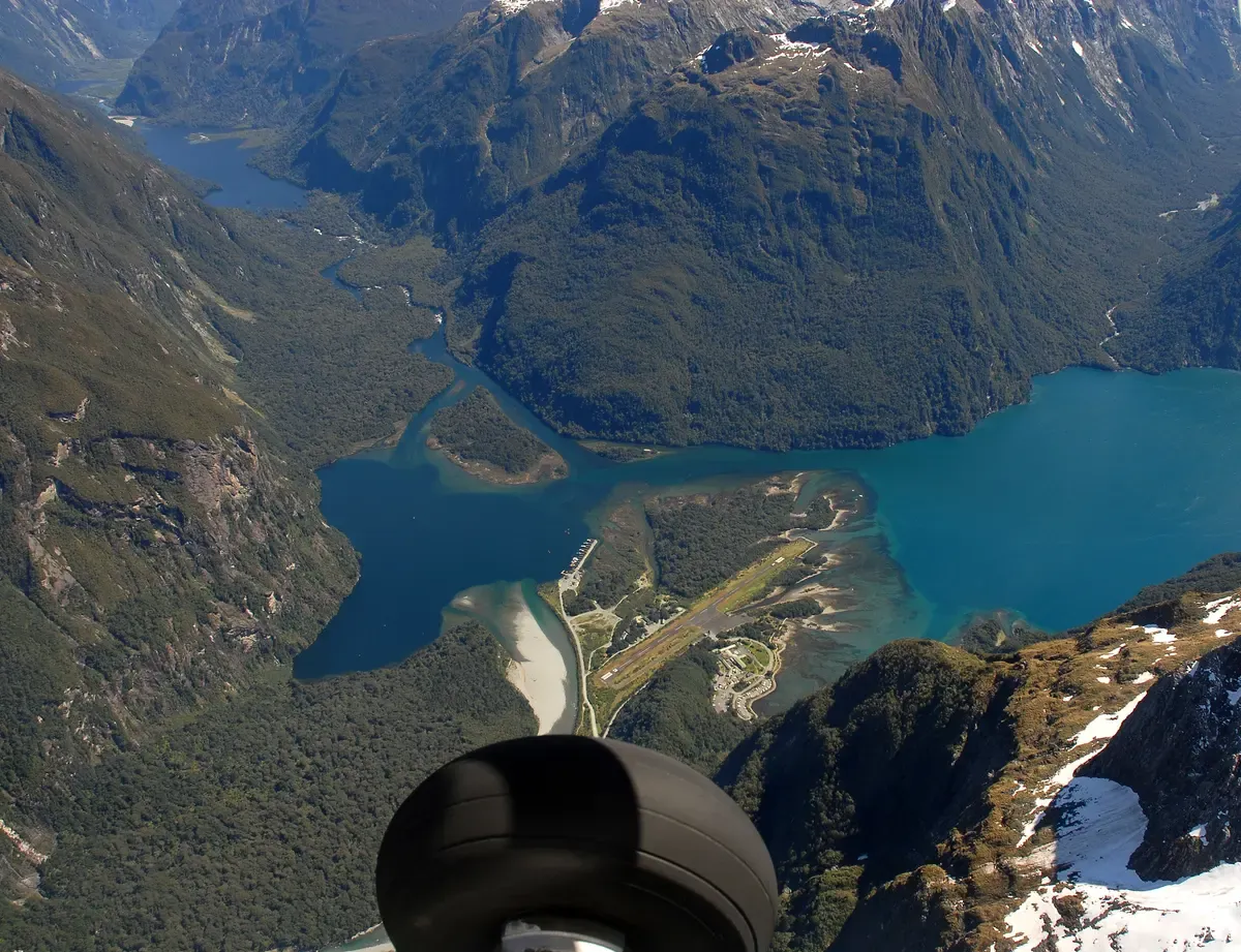 Aerial view over the Milford Sound area with the airstrip beyond the wing, on a flight before a Milford Sound cruise